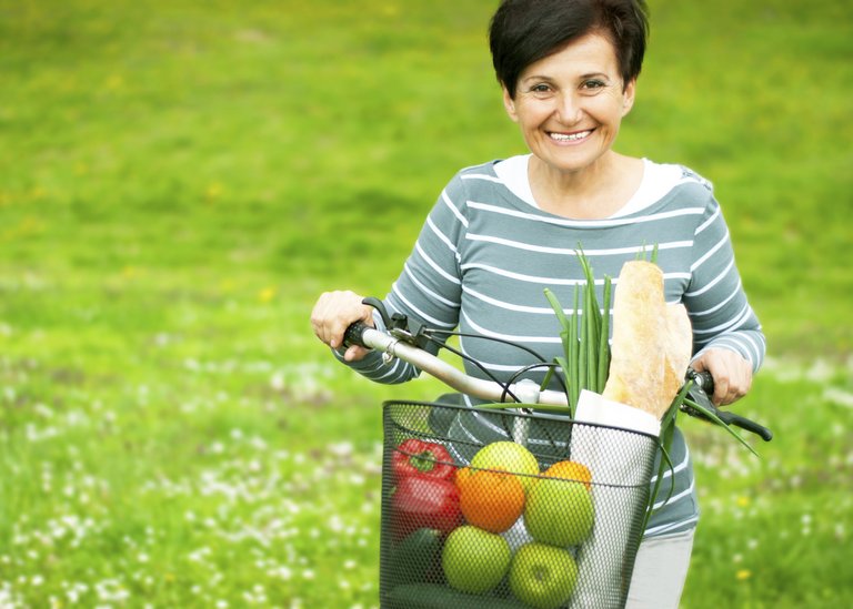 [Translate to Brasil - Portuguese:] Woman on a bike with healthy food in the basket