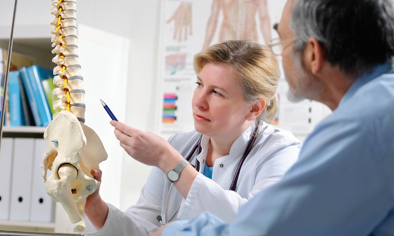 Médico explicando ao paciente possíveis complicações de doença óssea devido à DRC