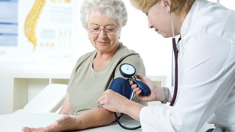 Médico medindo a pressão arterial de uma mulher