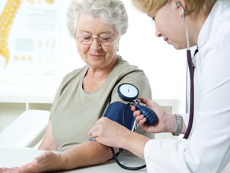 Médico medindo a pressão arterial de uma mulher
